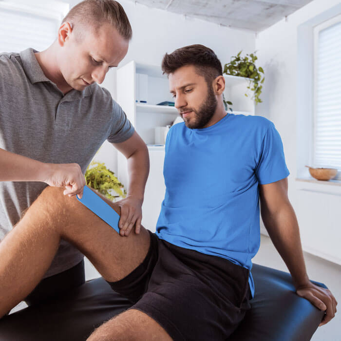 man getting his knee taped by athletic trainer